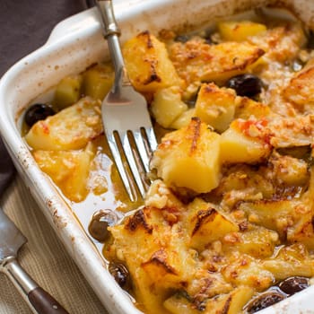Fish with potatoes and olives cooked in oven in small casserole
