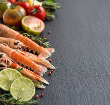 Raw langoustines with vegetables and herbs on the dark background