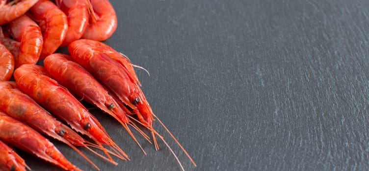 Many raw shrimps over dark background close up
