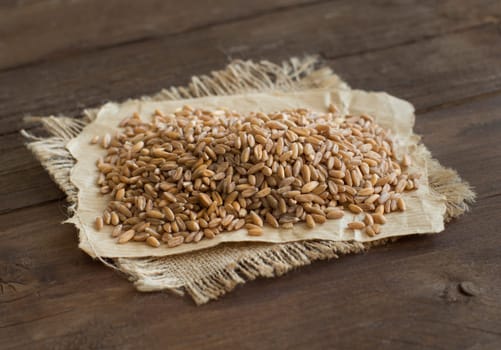 Pile of whole unpolished spelt on wooden table