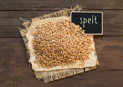 Whole unpolished spelt in a with a small chalkboard on wooden table