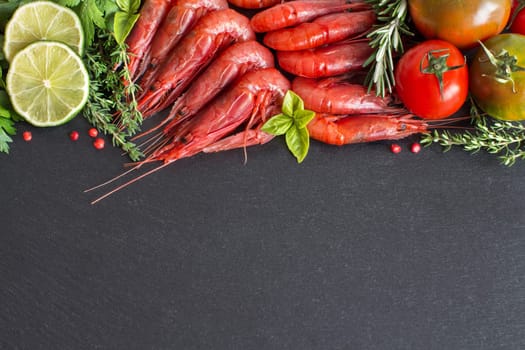 Raw shrimps with tomatoes, lime and herbs over dark background