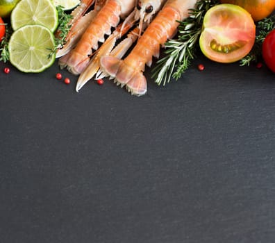 Raw langoustines with vegetables and herbs on the dark background