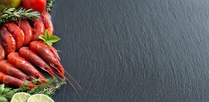 Raw shrimps with tomatoes, lime and herbs over dark background