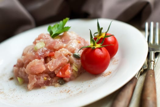 Delicious raw tuna tartare with fork and decorated with cherry tomatoes