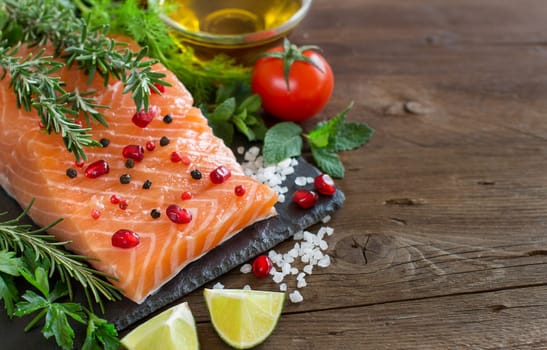 Salmon with vegetables, olive oil and herbs on wood