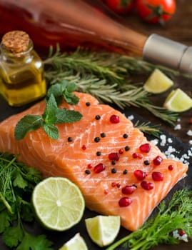 Salmon with vegetables, olive oil and herbs on wood