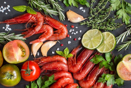 Raw shrimps with tomatoes, lime and herbs over dark background