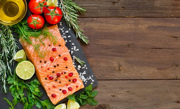 Salmon with vegetables and herbs on wooden background