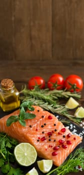 Salmon with vegetables, olive oil and herbs on wood