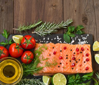 Salmon with vegetables, olive oil and herbs on wood