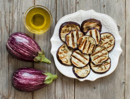 Grilled eggplants seasoned with olive oil on a wooden table