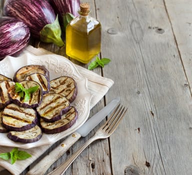 Grilled eggplants seasoned with olive oil on a wooden table