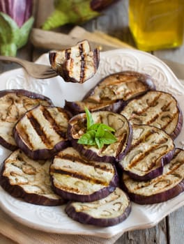 Grilled eggplants seasoned with olive oil on napkin on a wooden table