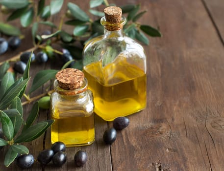 Olive oil and fresh olives on rustic wood background