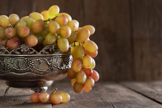 Grapes in silver bowl on an Old Wooden Background