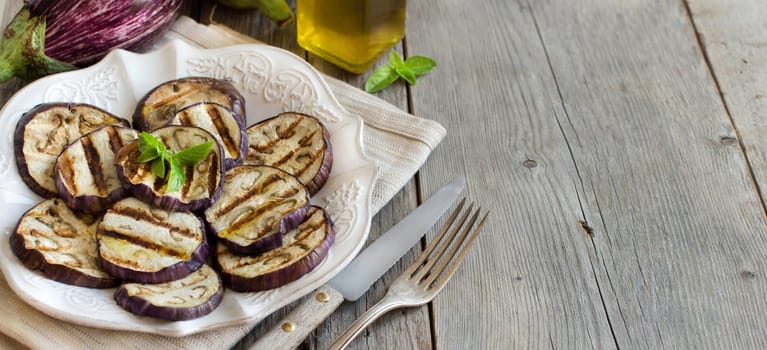 Grilled eggplants seasoned with olive oil on a wooden table