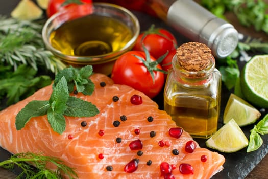 Salmon with vegetables, olive oil and herbs on wood