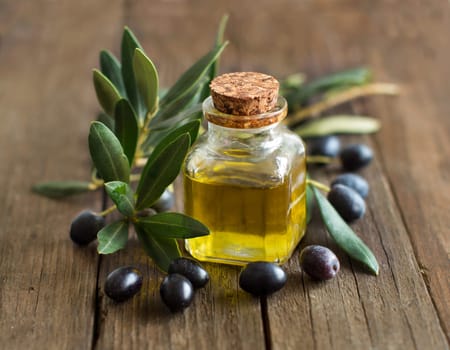Olive oil and fresh olives on rustic wood background