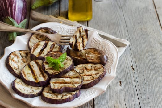 Grilled eggplants seasoned with olive oil on a wooden table
