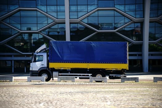 The side profile of a truck in front of a modern glass façade.