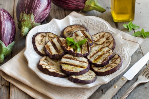 Grilled eggplants seasoned with olive oil on napkin on a wooden table