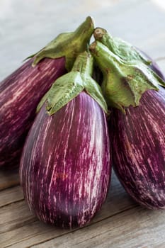 Fresh Raw striped eggplants on a old wooden table close up