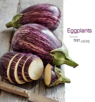 Fresh Raw striped eggplants and slices with knife on old wooden table
