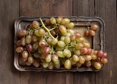Grapes on silver tray on an Old Wooden Background