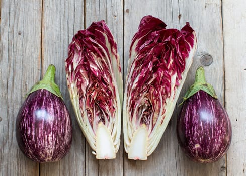 Striped eggplants and red chicory on a wooden table
