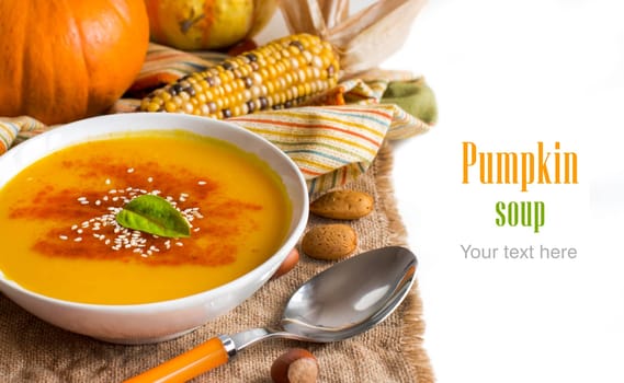 Fresh pumpkin soup with a spoon and vegetables on burlap