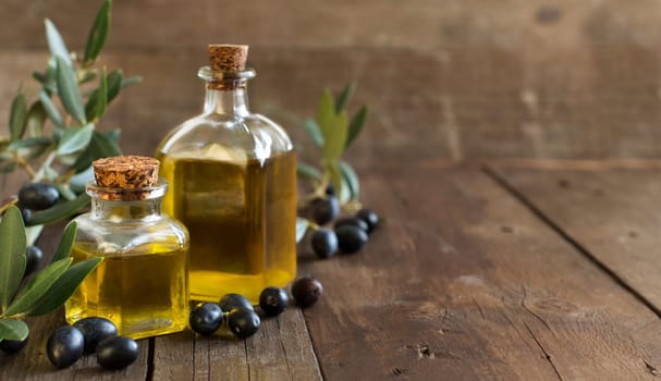 Olive oil and fresh olives on rustic wood background