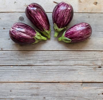 Four Fresh Raw striped eggplants on a old wooden table