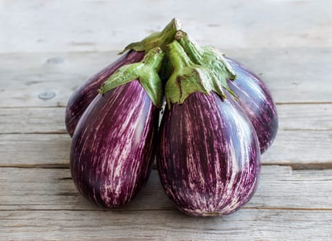 four Fresh Raw striped eggplants on a old wooden table