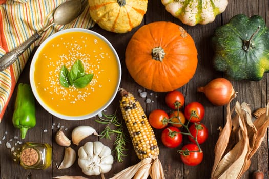 Fresh pumpkin soup and vegetables on a wooden table