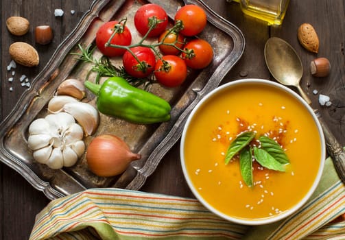 Fresh pumpkin soup and vegetables on a wooden table top view