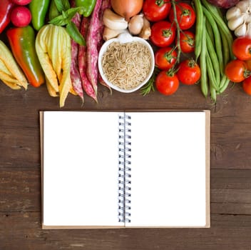 Unpolished raw rice and vegetables on a wooden background