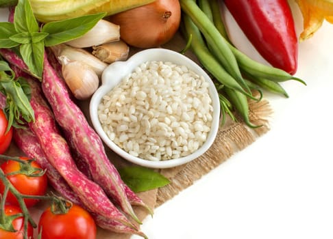 White rice in bowl and fresh vegetables on white