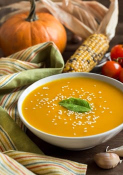 Fresh pumpkin soup and vegetables on a wooden table