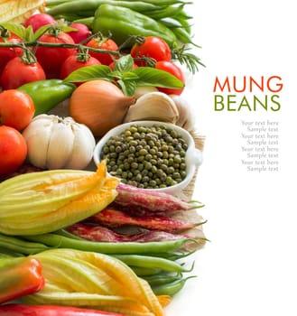 Raw organic mung beans in a bowl and vegetables isolated on white
