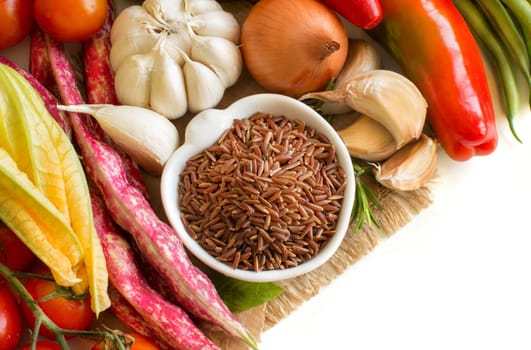 Red organic rice in bowl and fresh vegetables