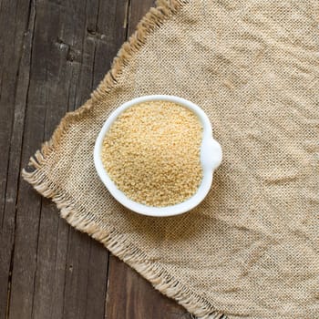 CousCous in a bowl on burlap and wooden table