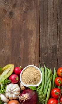 CousCous in a bowl and fresh vegetables on wood