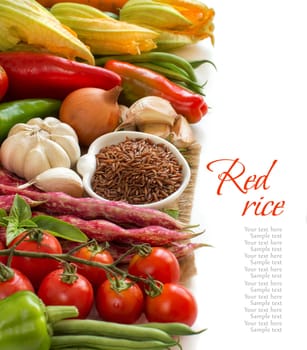 Raw red rice in a bowl and fresh vegetables isolated on white