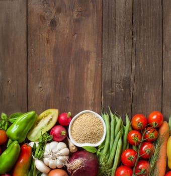 CousCous in a bowl and fresh vegetables on wood