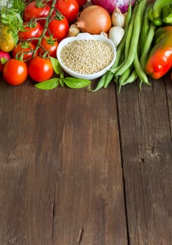 Quinoa in a bowl and fresh vegetables on a wooden table
