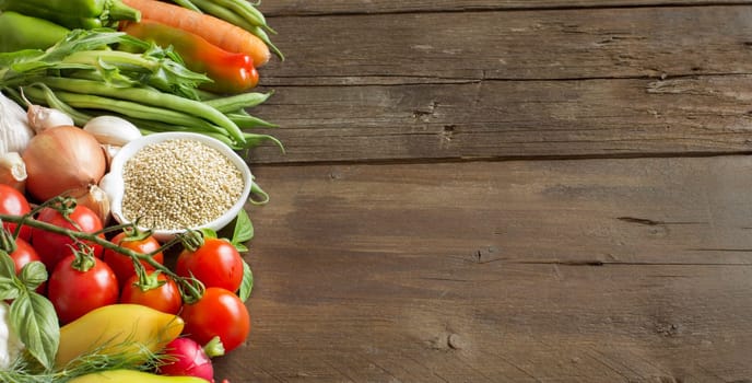 Quinoa in a bowl and fresh vegetables on a wooden table