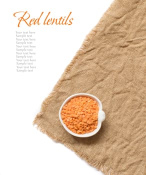 Red lentils in a bowl on burlap isolated on white