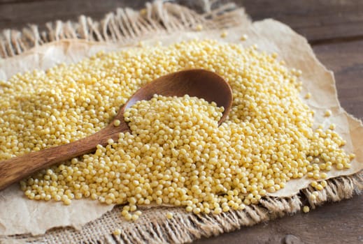 Raw millet with a spoon on burlap