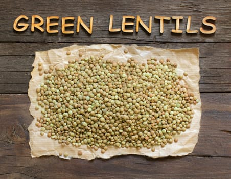 Green lentils on the dark table with wooden word Green Lentil